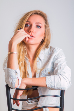 Young woman sitting on chair, fashion self confident pose, beauty conceptの写真素材