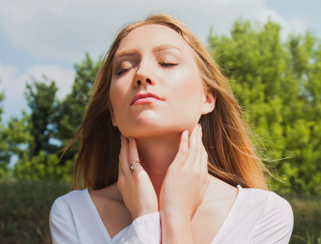 Close up portrait of young woman in white dress outdoor in nature, meditatingの写真素材