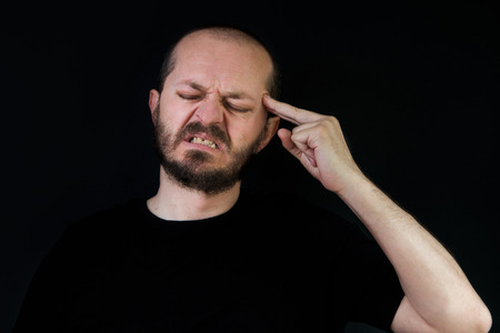 Serious man with beard and mustaches on black background in low key, frustration and despair gestureの写真素材