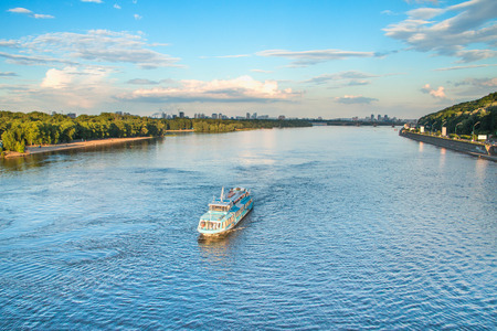 Tourist boat on the Dnepr River in Kiev, Ukraine, bridges and city skyline in backgroundの写真素材