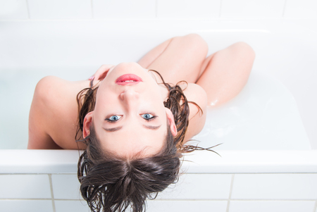 Beautiful young nude caucasian girl sitting in bath, top perspectiveの写真素材