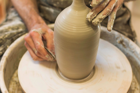 Potter creating a ceramics clay vase. Man sculptor in the workshop makes a jug out of earthenware...