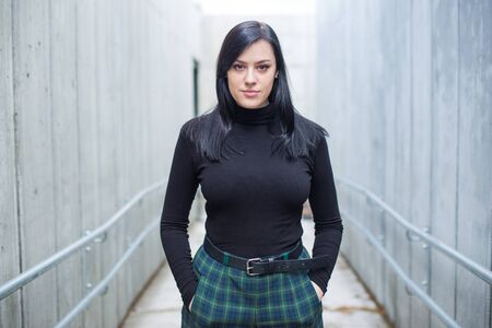 Confident young woman in black shirt and black hair walking on the street to underground in the city.の写真素材