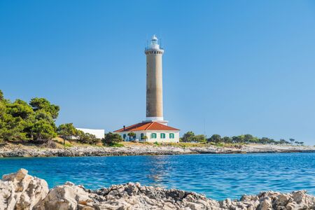 Croatia, island of Dugi Otok, old lighthouse of Veli Rat on the stone shore, beautiful seascape in foregroundの写真素材