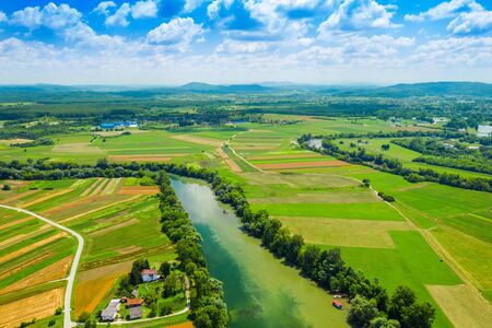 Rural countryside landscape in Croatia, Kupa river meandering between agriculture fields, shot from droneの写真素材