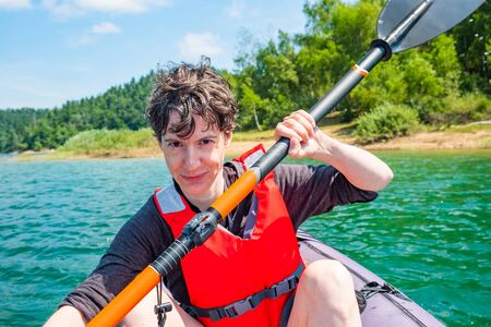 Woman paddling in inflatable kayak on lake Lokve, in Gorski kotar, Croatia. Adventurous experience in wild nature.の写真素材