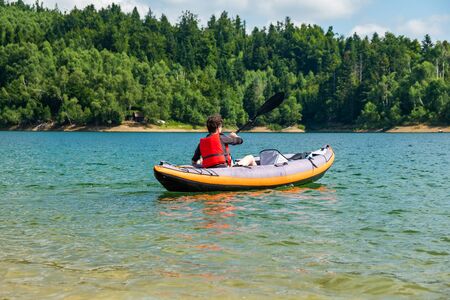 Woman paddling in inflatable kayak on lake Lokve, in Gorski kotar, Croatia. Adventurous experience in wild nature.の写真素材