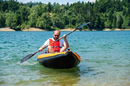 Man paddling in inflatable kayak on lake Lokve, in Gorski kotar, Croatia. Adventurous kayaking experience in a beautiful nature.の写真素材