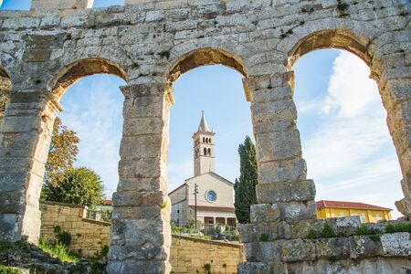 Ancient heritage in Pula, Istria, Croatia. Arches of monumental Roman arena. Detail of historic amphitheater, wide angle view of walls on blue sky background.の写真素材