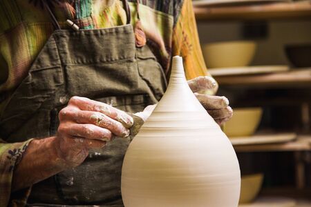 Potter in workshop forming ceramic vase on wheel. Hands detail.の写真素材