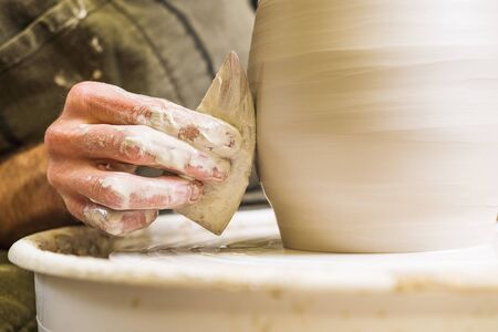 Potter in workshop forming ceramic vase on wheel. Hands detail.の写真素材