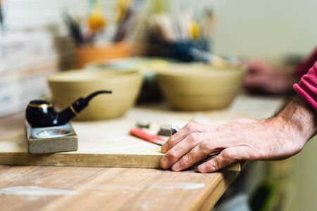Potter checking tools on pottery studio table, hands detail, shallow debt of field, small art...