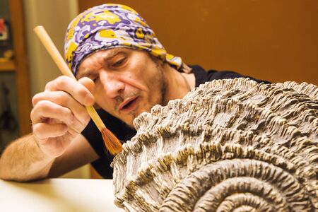 Dedicated artist potter painting colors on hand made aculpture, hands detail. Shallow debt of field,...