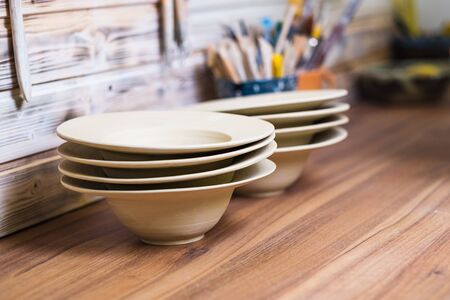Hand made plates, bawls and tools on pottery studio table, shallow debt of field, small art business conceptの写真素材