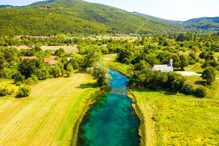 Croatia, beautiful green landscape, small church by Gacka river in region of Lika, aerial viewの写真素材