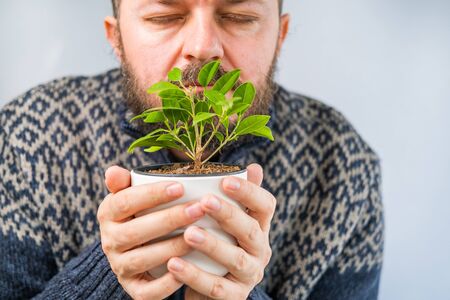 Bearded man holding and smelling the plant in hands, shallow debt of field, close upの写真素材