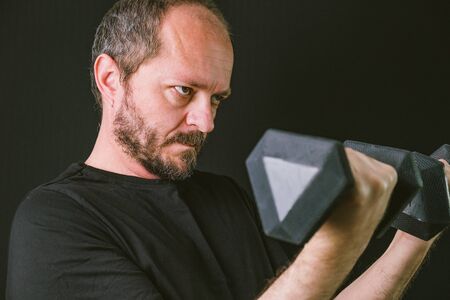 Fitness exercise, adult man training muscles at gym doing biceps with dumbbell weights, arms detailの写真素材