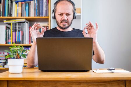 Man working from home office, on teleconference. Bearded man working online from home on computer...