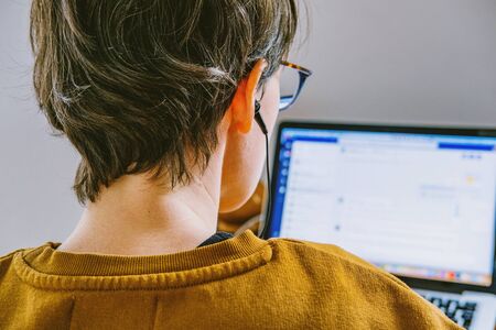 Woman working on desk in home office. Young Caucasian short hair woman with earphones working online...
