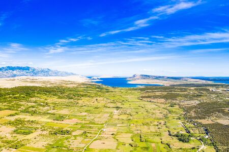 Croatia, Adriatic island of Pag, green valley with agriculture fields and Velebit mountain in backgroundの写真素材
