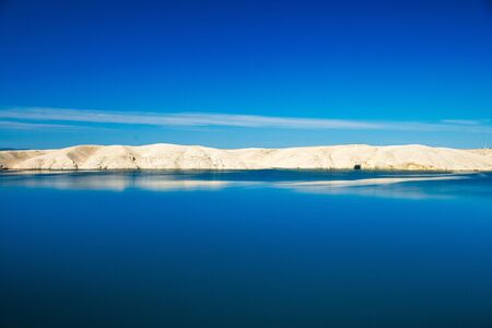 Croatia, Adriatic landscape, rocky desert of Pag island and peaceful seascape in the morning, reflection of stone in waterの写真素材