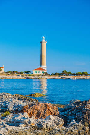 Lighthouse of Veli Rat on the island of Dugi Otok, Croatia, beautiful Adriatic seascape and rocks in foregroundの写真素材