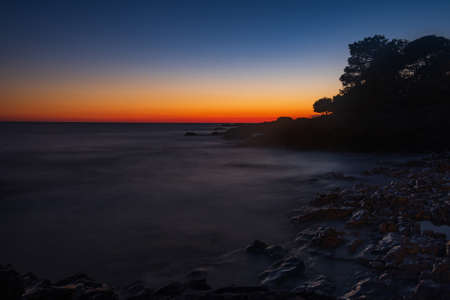 Beautiful evening on Adriatic Sea in Croatia, waves on rocks on shore of Dugi Otok island. Amazing sea sunset and red sky on horizon. Long exposure.の写真素材