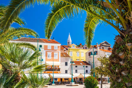 Town of Mali Losinj on the island of Losinj, Adriatic coast in Croatia, cathedral tower and city center, view through the palm leavesの写真素材