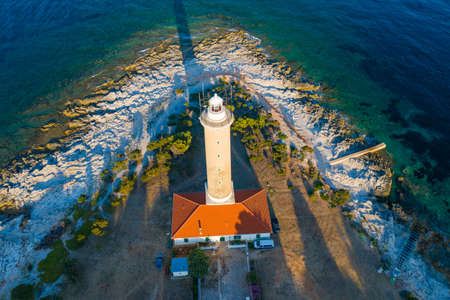 Aerial view of lighthouse tower of Veli Rat on the island of Dugi Otok, Croatia in early morning, Adriatic sea in backgroundの写真素材