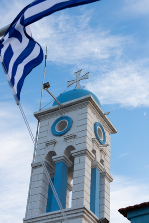 Greek blue-white flag waving in front of the bell tower of a church/monasteryの写真素材