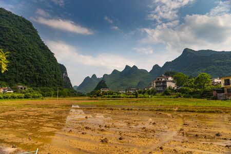 Mountains surrounding the houses and the farms (fields) in a farming village outside Yangshuo, Chinaの写真素材