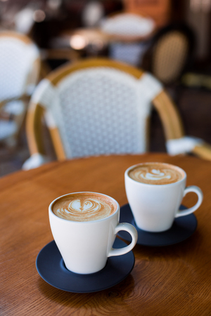 Cups of cappuccino with latte on wodden table.の写真素材