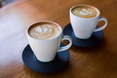 Cups of cappuccino with latte on wodden table.の写真素材