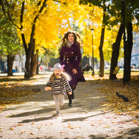 Mother and her child girl playing together on autumn walk in nature outdoors.の写真素材
