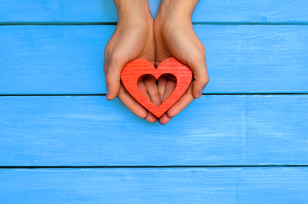 red wooden heart in hands on a blue wooden background

の写真素材