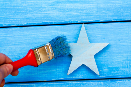 brush in hand colors blue wooden star on a blue background



の写真素材