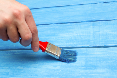 painting on wood, hand with a brush, blue wood, housework;の写真素材