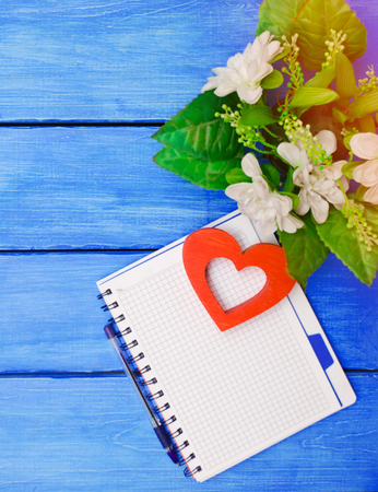 notebook with pen, flowers, on a blue wooden backgroundの写真素材