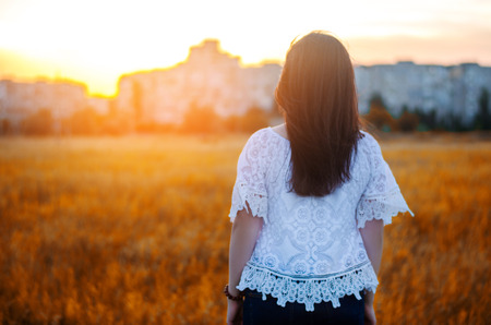 Young woman admires the sunset  back view.  outdoor. summer. view of the city. life style