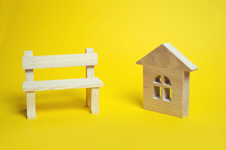 Wooden house and bench on a yellow background. The concept of the real estate market. Prices demand offer rent taxes banks affordable housing.の写真素材