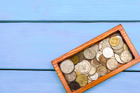 box with coins of countries of the world on a blue wooden background. money. a Palestinian, a Soviet, an Israeli, a Ukrainian coinの写真素材