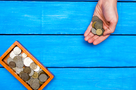 money in hand, casket with coins on a blue wooden background,  space for text



の写真素材