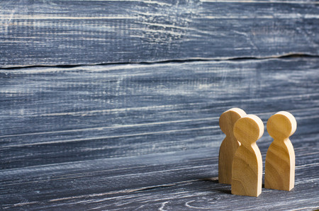 Three wooden human figures stand together. Social concept, family, team, friends, brothers and sisters. Space for text.の写真素材