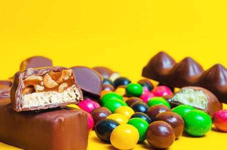 chocolate bars, colorful candies, sweets on a yellow backgroundの写真素材