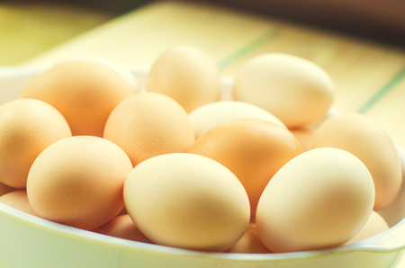 white and brown fresh chicken eggs in a plate. concept of easter. cooking ingredientsの写真素材