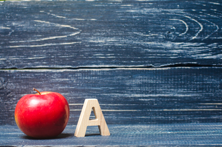 Red apple and letter A on a dark background of a school board. The concept of primary education. Apple for the teacher. Sadik, school, college, university, educational institution. Alphabet. Score A.の写真素材