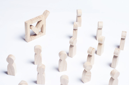 A crowd of people looks at the wooden tick in the box. The concept of the political process and democratic elections. The choice of society, president, parliament. Referendum, forum, meeting. Victory.の写真素材