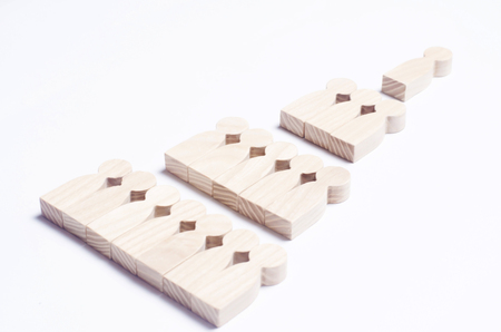 Wooden figures of people on a white background in the form of a pyramid of social hierarchy. The concept of relations in society and the company's business, collective. Political system.の写真素材