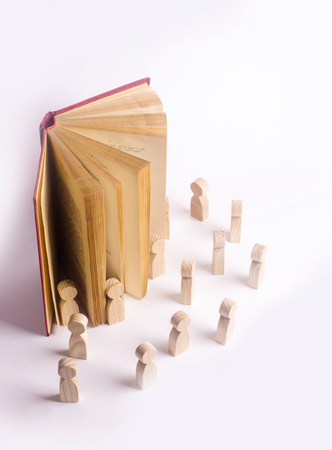 Miniature figures of people come out of the book into the real world. The book comes alive, the characters come out of the book into the real world. The concept of adventure. Propaganda reading booksの写真素材