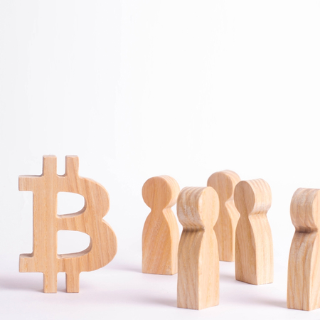 Wooden figures of people are standing near a bitcoin on a white background. Crypto currency, blockchain technology. The collapse and rise cost of bitcoin. Mining farms, miners, stock exchange cryptsの写真素材
